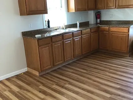a kitchen with granite countertop a sink cabinets and wooden floor
