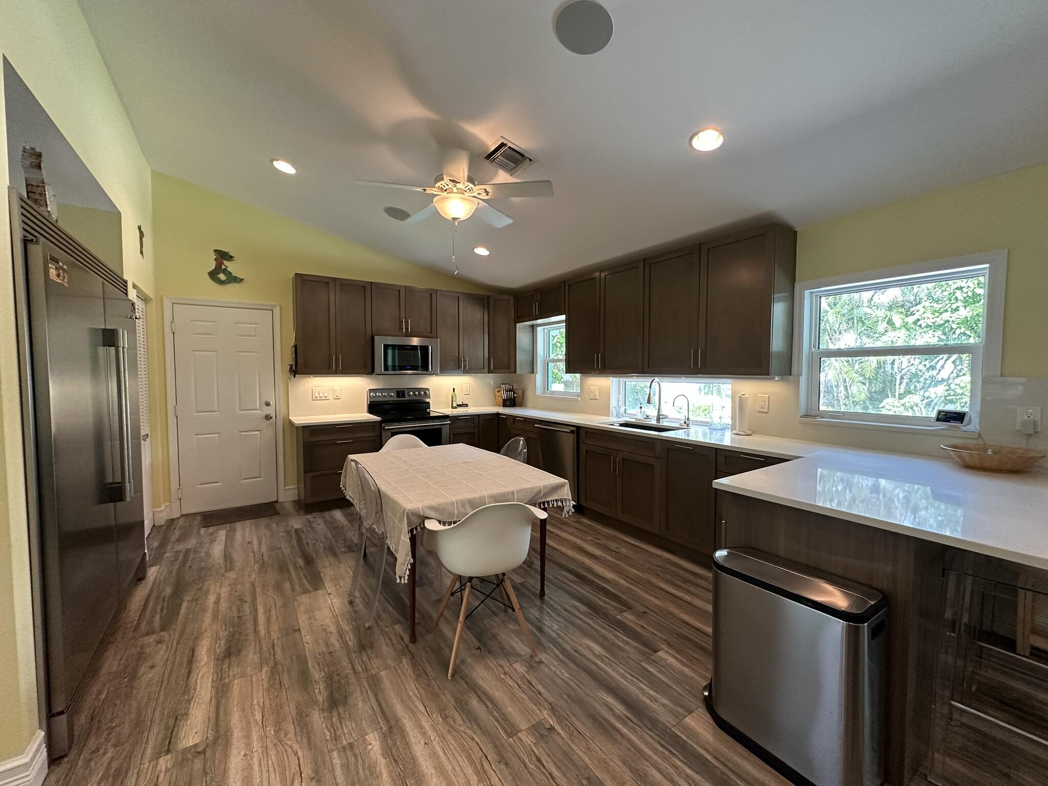 2415 Laurel Lane Palm Beach Gardens, FL 33410 - Photo 8 of 18 a kitchen with stainless steel appliances a sink a stove a refrigerator cabinets and living room view