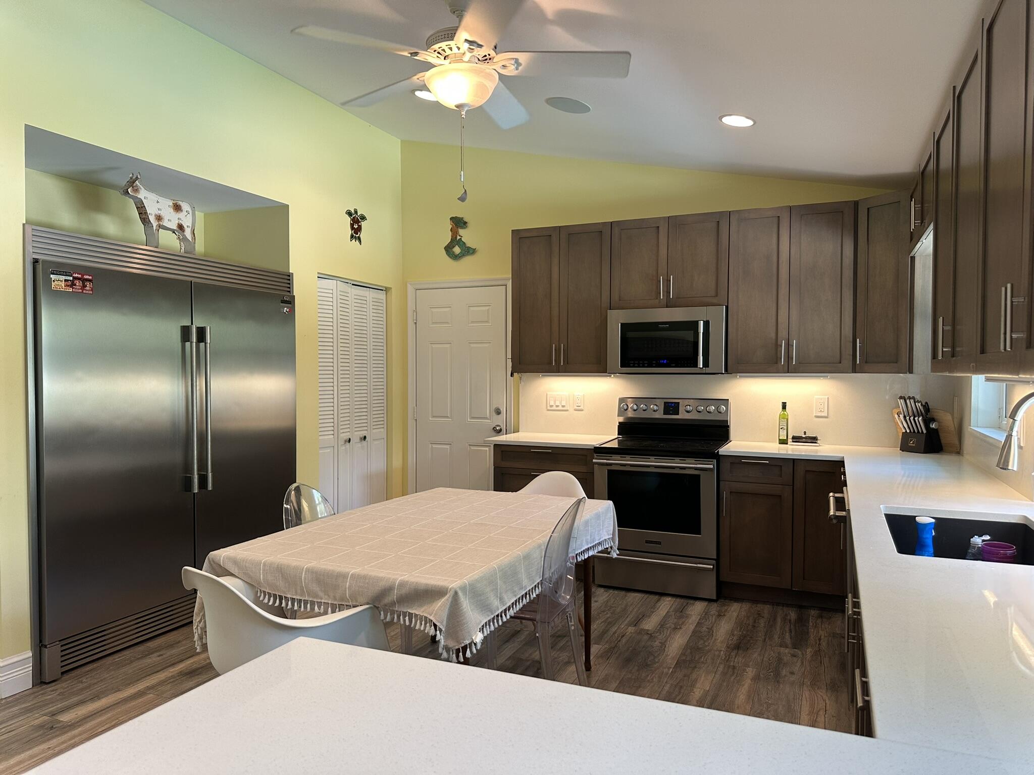 2415 Laurel Lane Palm Beach Gardens, FL 33410 - Photo 9 of 18 a large kitchen with a refrigerator a stove a sink a dining table and chairs