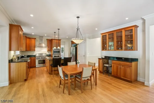 a kitchen with stainless steel appliances granite countertop a stove top oven a sink dishwasher a dining table and chairs with wooden floor