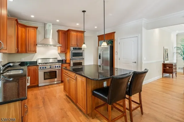 a kitchen with stainless steel appliances granite countertop a stove top oven a sink dishwasher a dining table and chairs with wooden floor