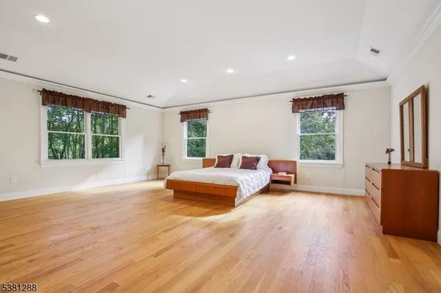 a spacious bedroom with a large window and a wooden floor