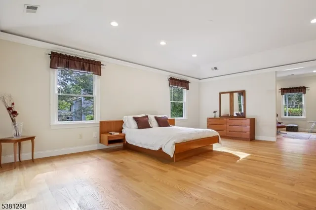 a spacious bedroom with a large bed and wooden floor