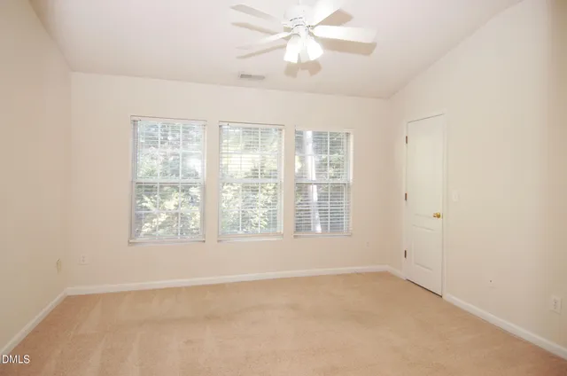 an empty room with chandelier fan and windows