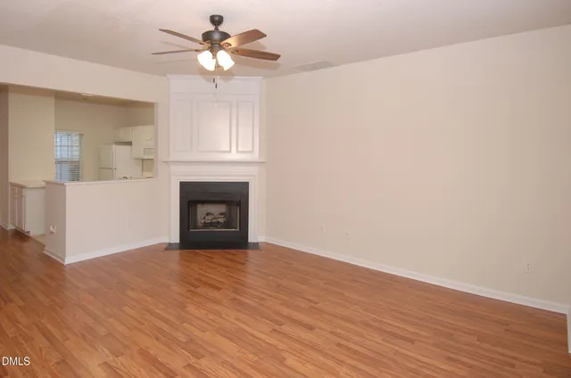 a view of an empty room with wooden floor and a fireplace