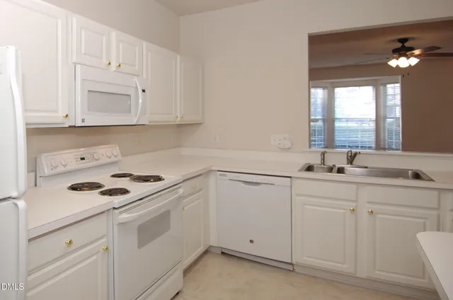a kitchen with white cabinets and white appliances