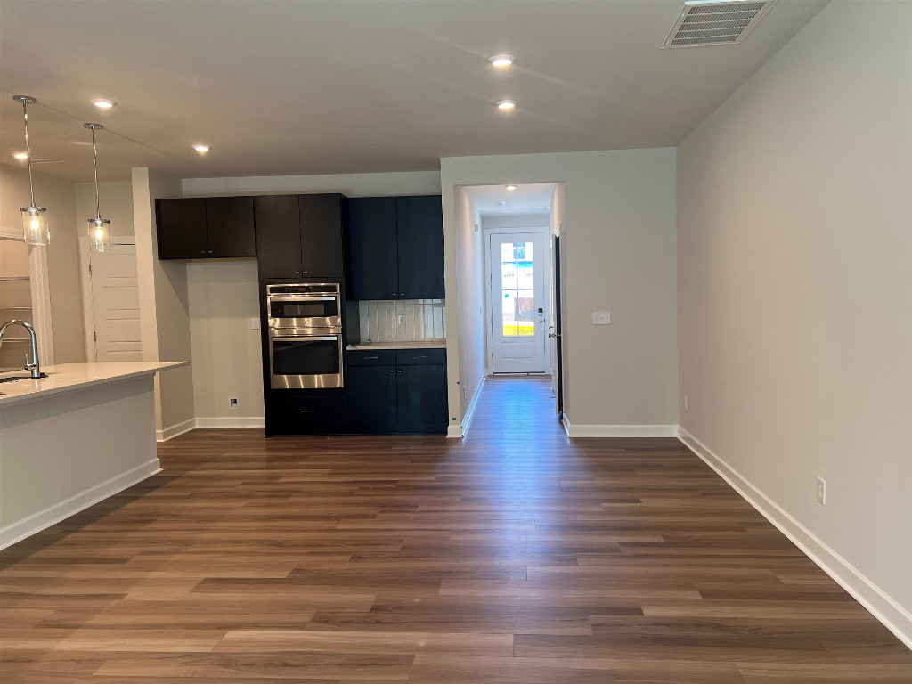 7809 Sofiana Avenue Raleigh, NC 27617 - Photo 10 of 20 an empty room with wooden floor kitchen view and windows