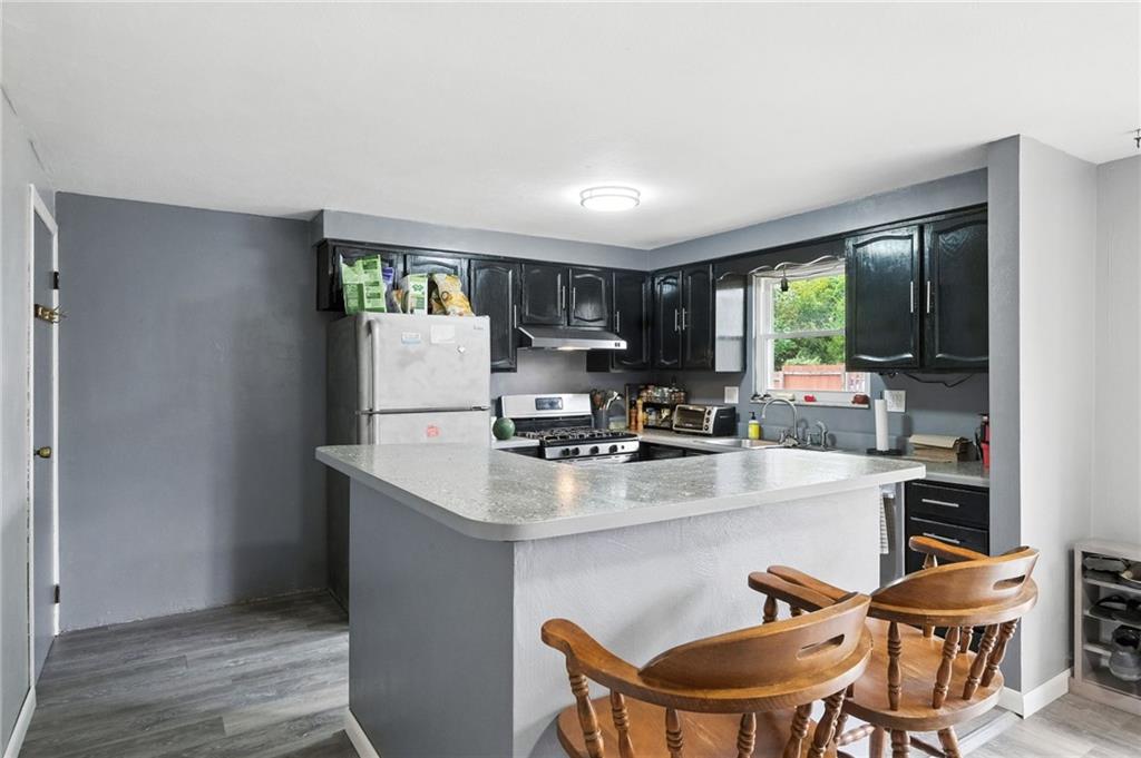 553 Indus Street Pittsburgh, PA 15207 - Photo 9 of 41 a kitchen with stainless steel appliances granite countertop a stove a refrigerator a sink a dining table and chairs with wooden floor