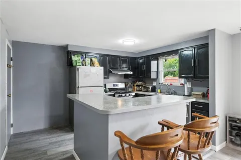 a kitchen with stainless steel appliances granite countertop a stove a refrigerator a sink a dining table and chairs with wooden floor