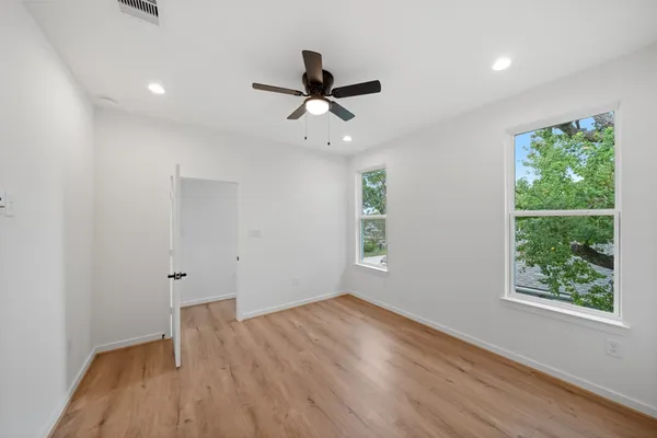 a view of an empty room with a window and wooden floor