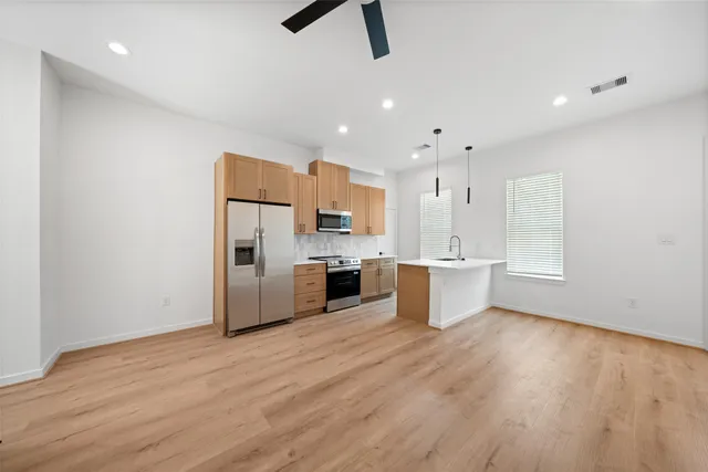 a kitchen with stainless steel appliances kitchen island hardwood floor sink and stove