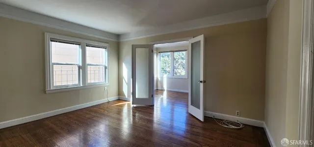 a view of an empty room with wooden floor and a window