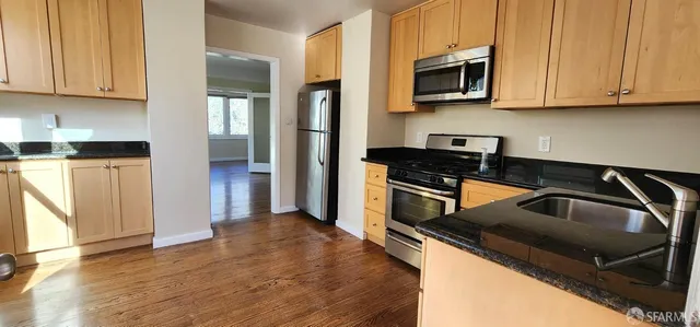 a kitchen with granite countertop a stove a sink and a microwave