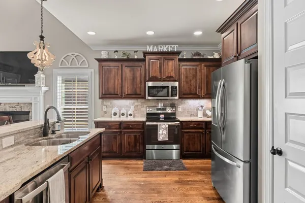 a kitchen with stainless steel appliances granite countertop a refrigerator a stove a sink and a microwave