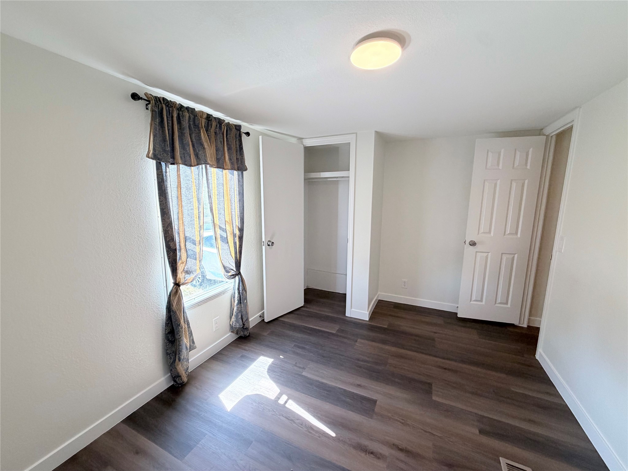 Rich wood plank flooring accents a versatile bedroom space with built-in closet storage.
