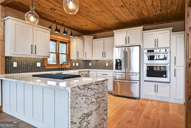 a large kitchen with granite countertop a sink and cabinets
