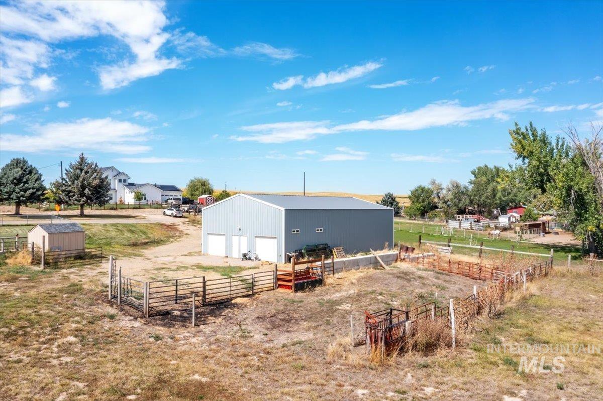7900 Labor Camp Road Caldwell, ID 83607 - Photo 44 of 45 Property featuring a metal roof structure, paved driveway, expansive green lawn areas, mature trees, and a separate outbuilding