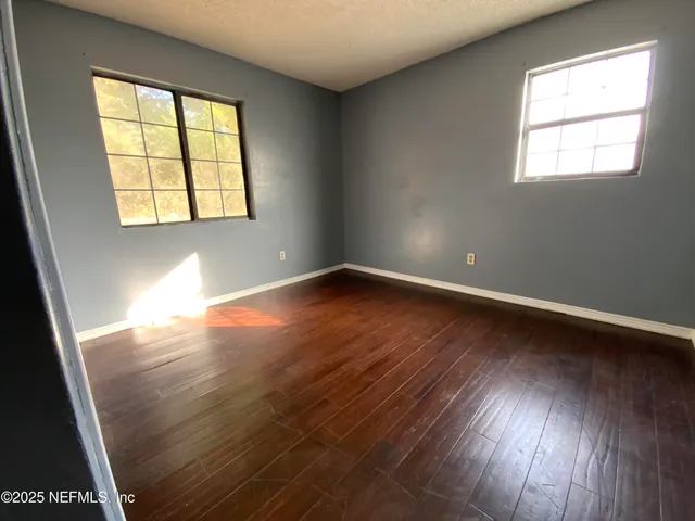 a view of an empty room with wooden floor and closet