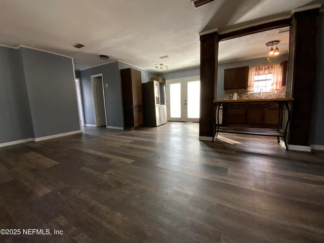 a view of an empty room with wooden floor and a fireplace