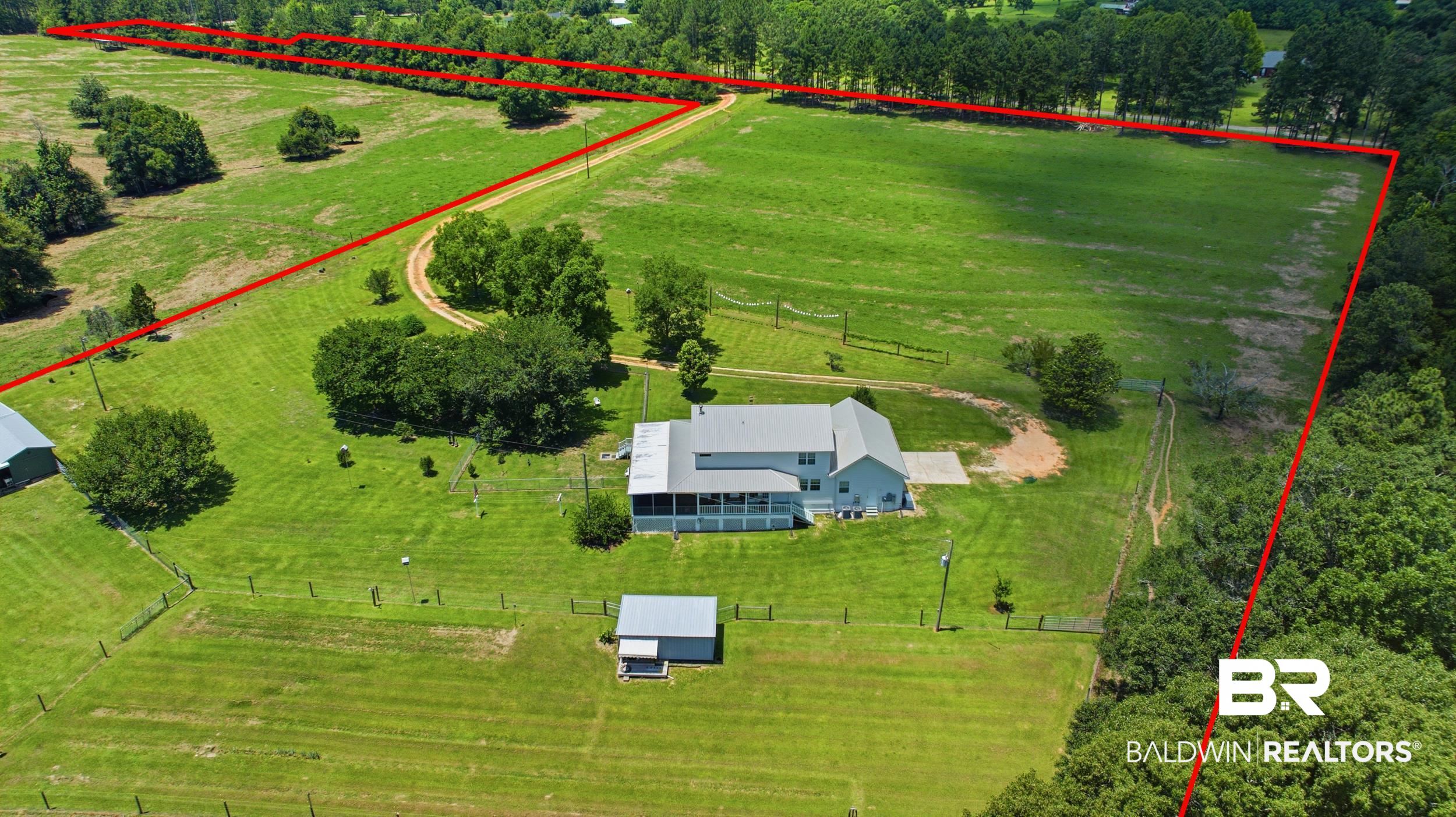 15855 Calvin Richerson Road Bay Minette, AL 36507 - Photo 62 of 83 Expansive property featuring a residence with a covered porch, a separate outbuilding, a long gravel driveway, and extensive perimeter fencing