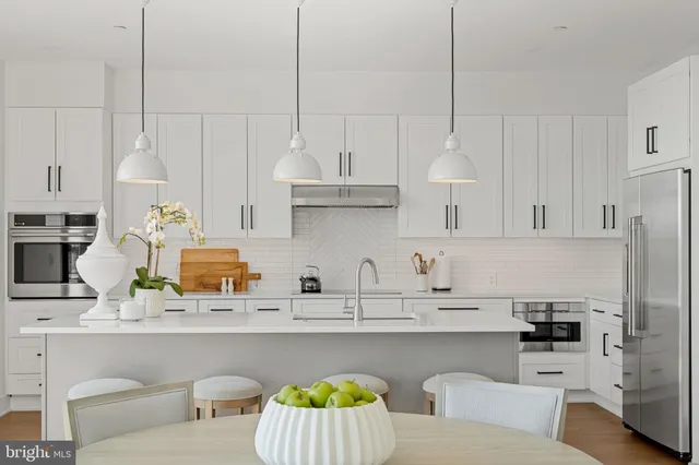 a kitchen with stainless steel appliances a sink stove and wooden floor