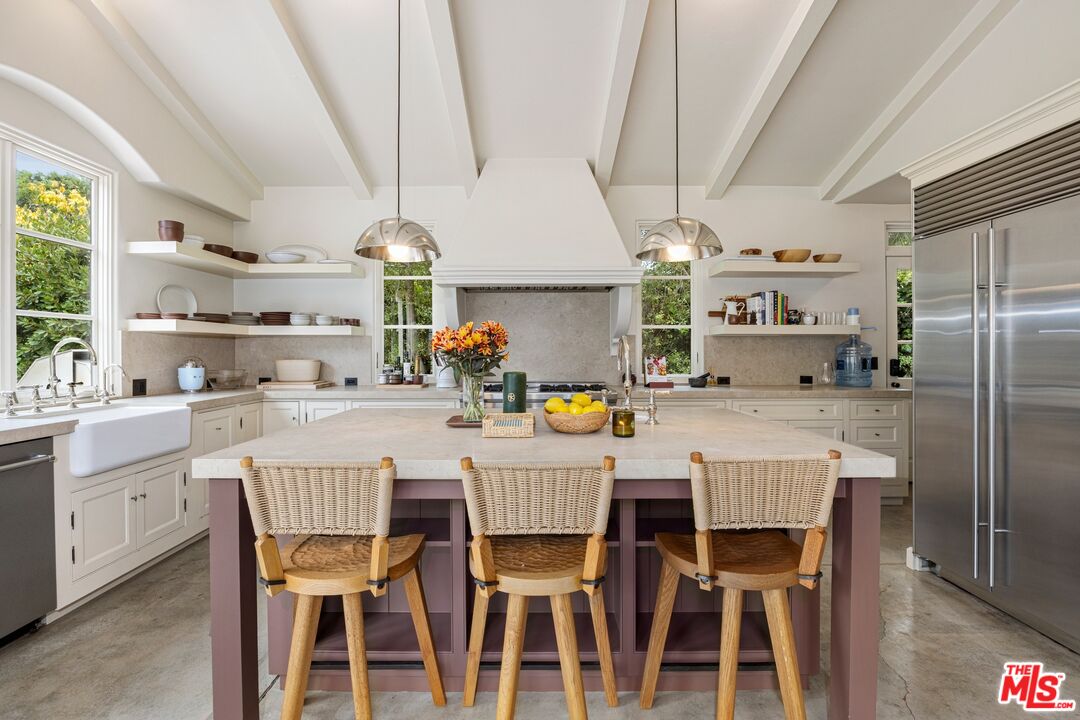 765 Ranch Lane Pacific Palisades, CA 90272 - Photo 6 of 23 a kitchen with stainless steel appliances a dining table chairs and a refrigerator