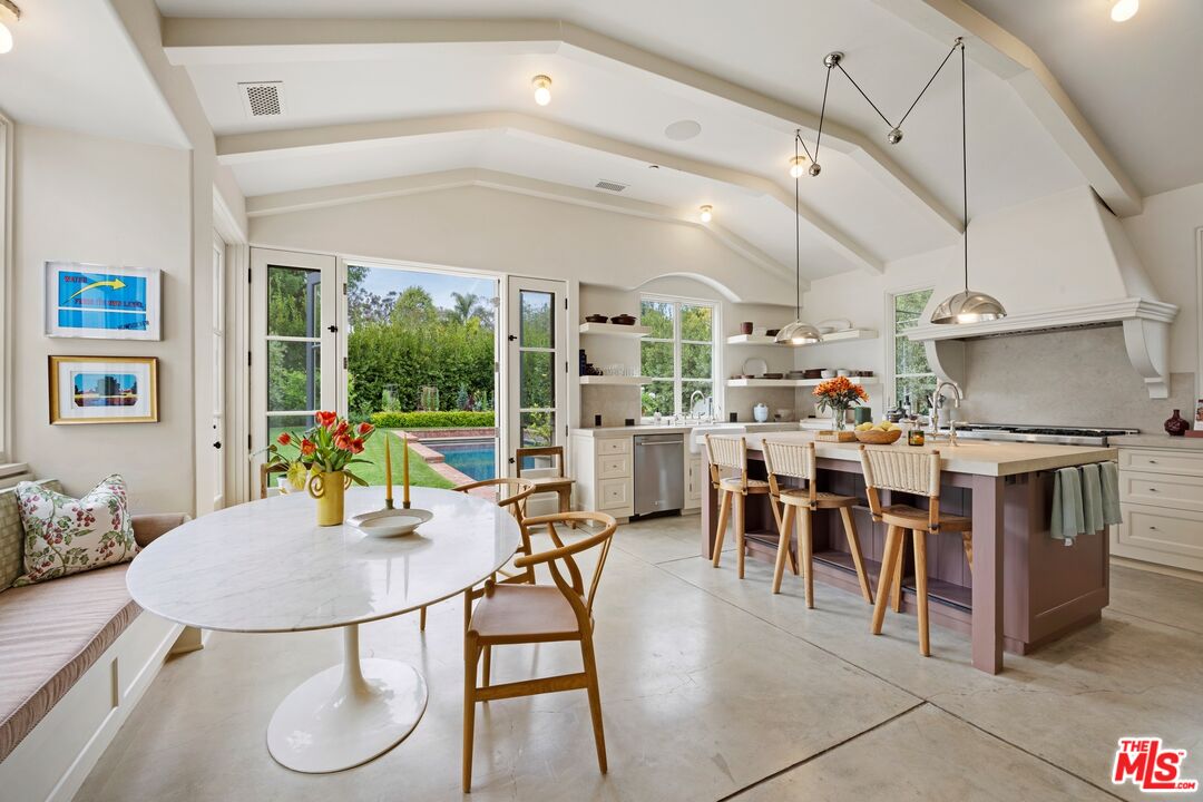 765 Ranch Lane Pacific Palisades, CA 90272 - Photo 7 of 23 a kitchen with stainless steel appliances kitchen island granite countertop a table chairs and a refrigerator