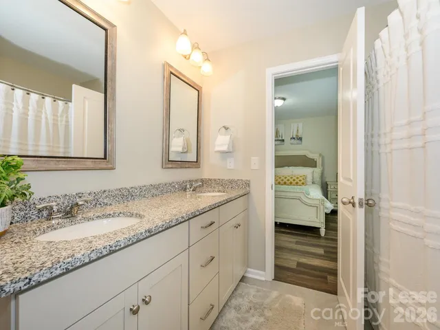 a en suite bathroom with a granite countertop sink and a mirror