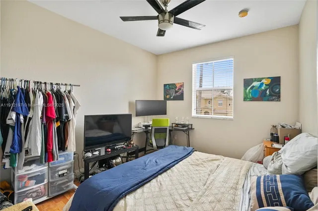 a bedroom with a bed a flat screen tv and a window