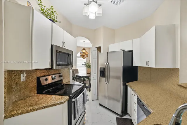 a kitchen with stainless steel appliances granite countertop a refrigerator a stove and a sink