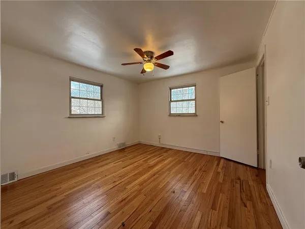 a view of an empty room with window and wooden floor