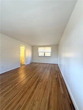 a view of empty room with window and wooden floor