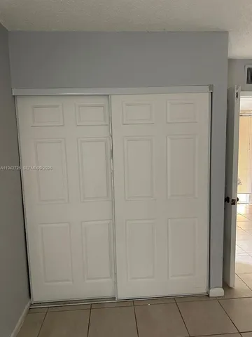 an empty room with wooden floor chandelier fan and windows