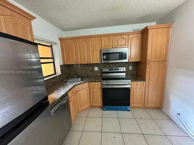 a kitchen with granite countertop a stove a sink and a microwave