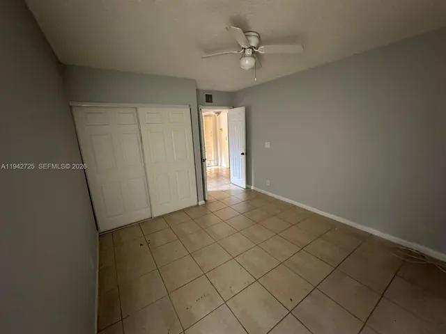 an empty room with a ceiling fan and carpet