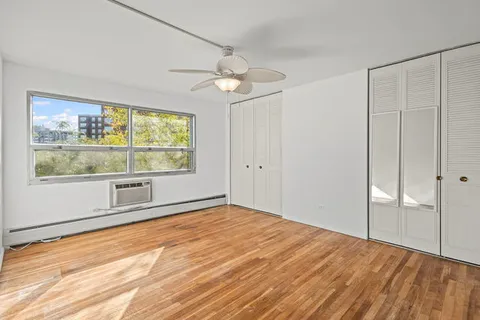 a view of an empty room with a window and wooden floor