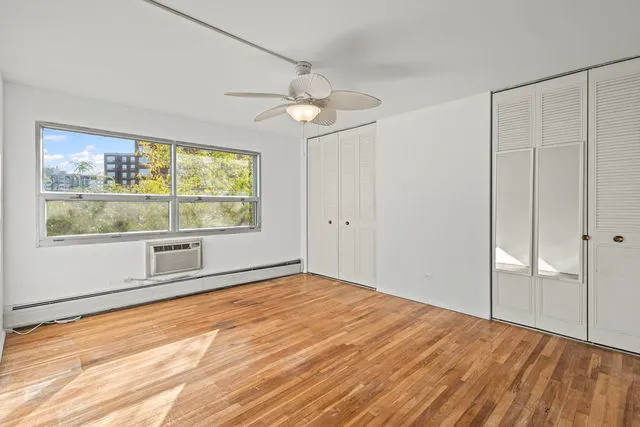 a view of an empty room with a window and wooden floor