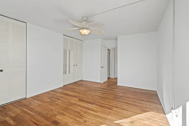 a view of empty room with wooden floor and fan