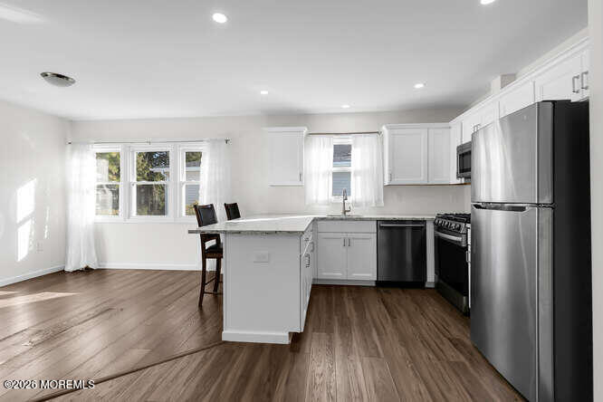 8 Carter Way Brick, NJ 08723 - Photo 4 of 27 a kitchen with a refrigerator wooden floor and wooden cabinets