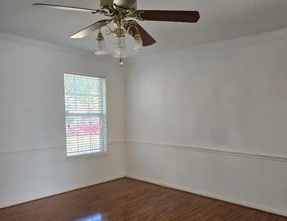 an empty room with wooden floor chandelier fan and windows