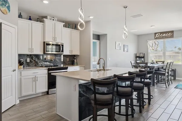 a kitchen with stainless steel appliances kitchen island granite countertop a table chairs sink and cabinets
