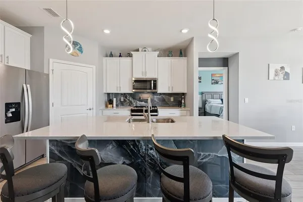a kitchen with granite countertop a dining table chairs stove a sink and dishwasher