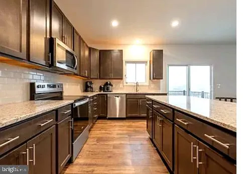 a kitchen with stainless steel appliances kitchen island granite countertop a refrigerator and a stove top oven