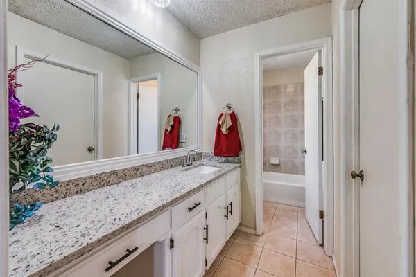 a bathroom with a granite countertop sink and a mirror