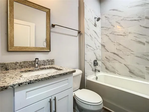 a bathroom with a granite countertop sink toilet and shower