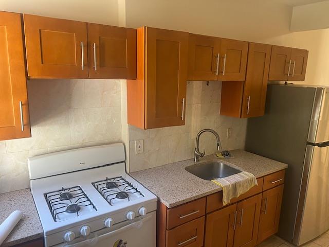 88-40 88th Street Queens, NY 11421 - Photo 14 of 18 Kitchen with stainless steel fridge, sink, gas range gas stove, and backsplash