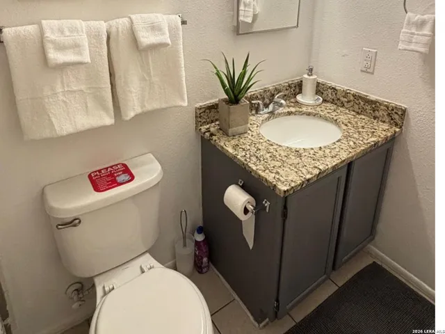 a bathroom with a granite countertop toilet sink and mirror