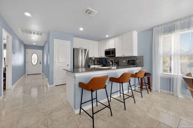 a kitchen with stainless steel appliances kitchen island granite countertop a refrigerator and microwave