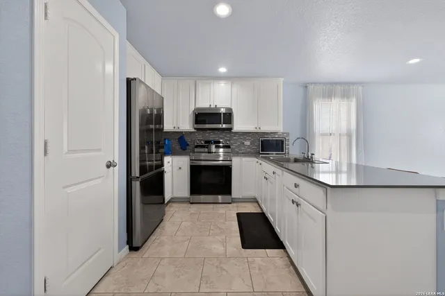 a kitchen with stainless steel appliances granite countertop a refrigerator and a stove top oven