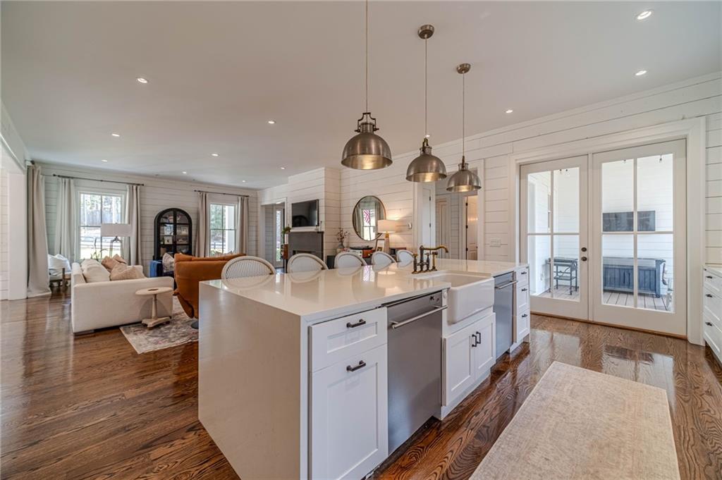 220 Audreys Way Suwanee, GA 30024 - Photo 22 of 66 a large white kitchen with a large island oven a sink dishwasher and a dining table with wooden floor